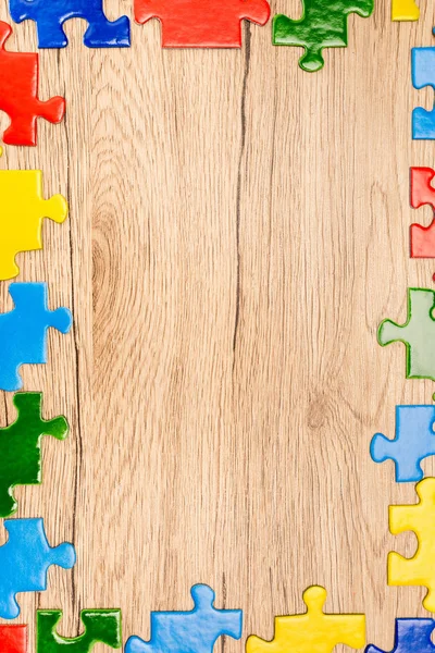 Vista superior de piezas de colores del rompecabezas sobre fondo de madera, concepto de autismo - foto de stock