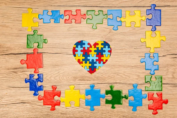 Vista dall'alto del cuore decorativo con pezzi di puzzle su sfondo di legno, concetto di autismo — Foto stock