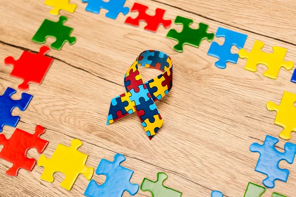High angle view of awareness ribbon with pieces of puzzle on wooden background, autism concept — Stock Photo