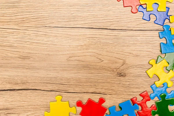 Vista superior de peças multicoloridas de quebra-cabeça em fundo de madeira, conceito de autismo — Fotografia de Stock