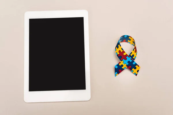 Vista superior de la cinta de conciencia y tableta digital sobre fondo blanco, concepto de autismo - foto de stock