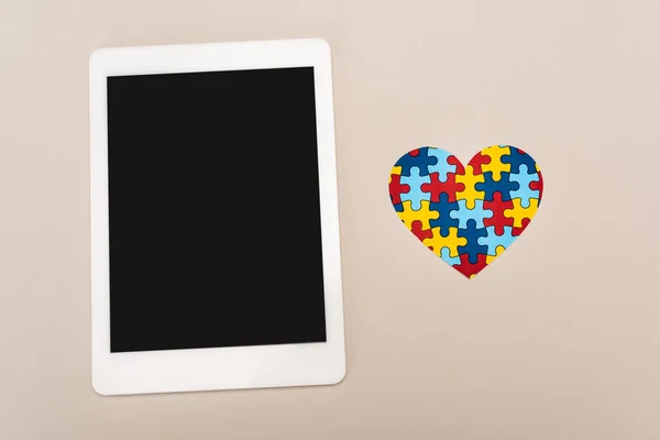 Vista dall'alto del cuore puzzle e tablet digitale su sfondo bianco, concetto di autismo — Foto stock