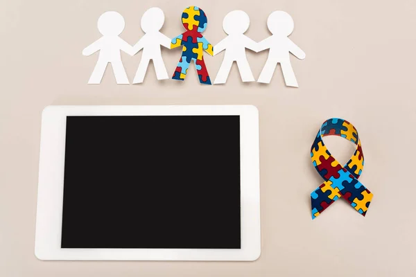 Top view of awareness ribbon, digital tablet and special kid with autism among another on white background — Stock Photo