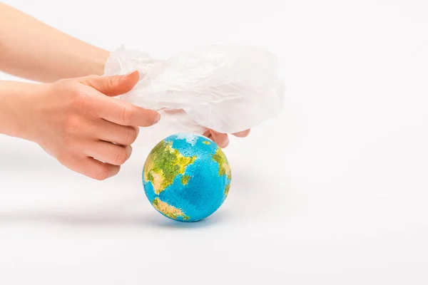 Vue recadrée de la femme tenant un sac en plastique au-dessus du globe sur le concept de réchauffement climatique blanc — Photo de stock