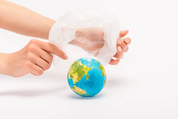 Partial view of woman holding plastic bag above globe on white, global warming concept — Stock Photo