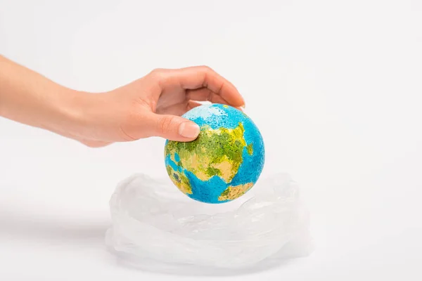 Vue recadrée de la femme mettant le globe dans un sac en plastique sur blanc, concept de réchauffement climatique — Photo de stock