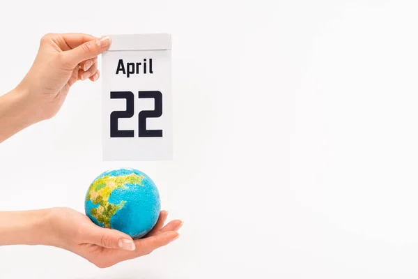 Cropped view of woman holding calendar with 22 april inscription and globe on white background, earth day concept — Stock Photo