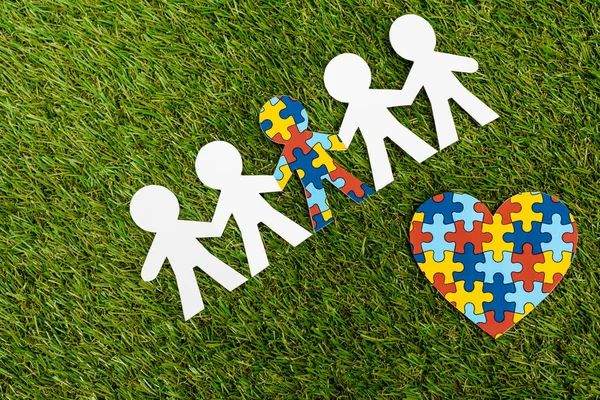 Top view of special kid with autism among another and decorative heart on green background — Stock Photo