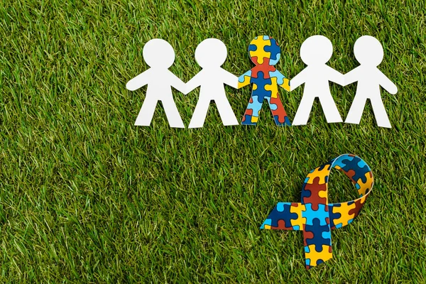 Top view of special kid with autism among another and awareness ribbon on green background — Stock Photo