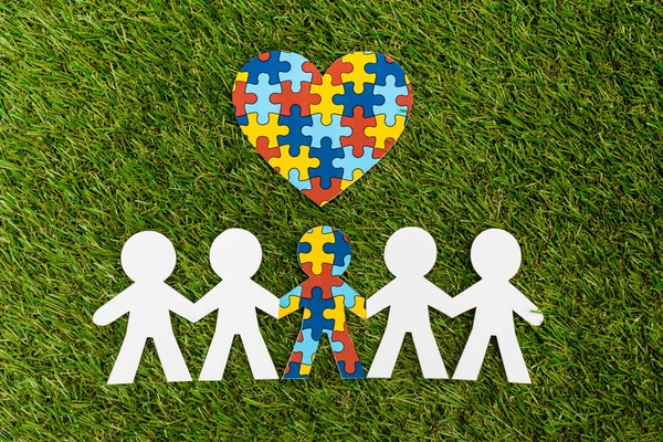 Draufsicht auf spezielle Kinder mit Autismus inmitten eines anderen und dekorativen Puzzle-Herzens auf Grün — Stockfoto