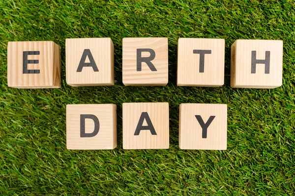 Top view of cubes with earth day lettering on green — Stock Photo