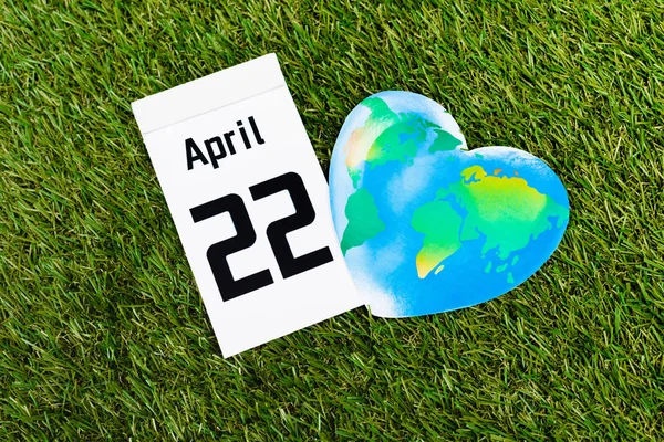 Top view of calendar with 22 april inscription and globe on green background, earth day concept — Stock Photo