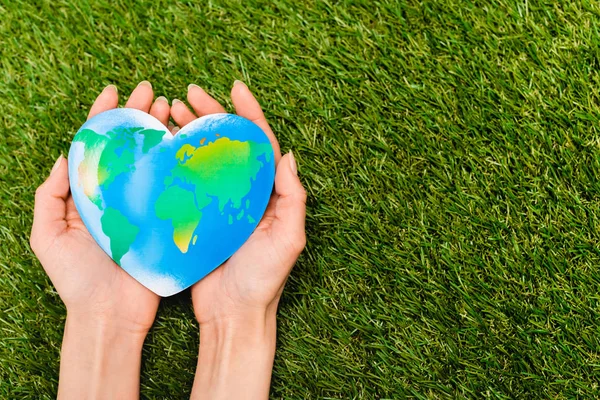 Vue recadrée du globe dans les mains féminines sur vert, concept de jour de la terre — Photo de stock
