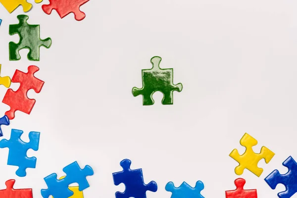 Vista superior de piezas brillantes del rompecabezas sobre fondo blanco, concepto de autismo - foto de stock