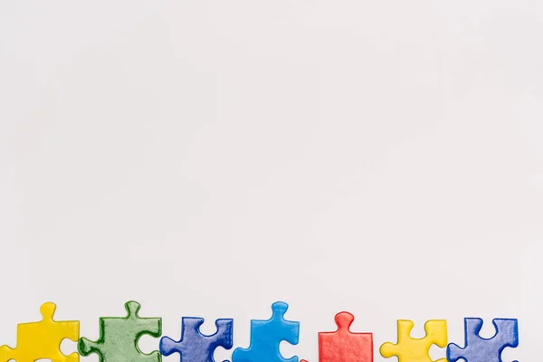 Vista superior de piezas coloridas de rompecabezas aislado en blanco, concepto de autismo - foto de stock