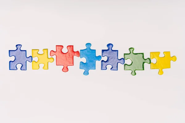 Top view of multicolored pieces of puzzle isolated on white, autism concept — Stock Photo