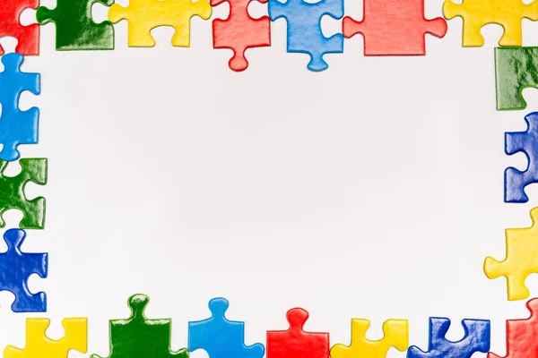 Vista superior do quadro com peças brilhantes de quebra-cabeça no branco, conceito de autismo — Fotografia de Stock