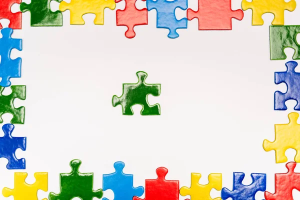 Top view of frame with bright pieces of puzzle on white background, autism concept — Stock Photo