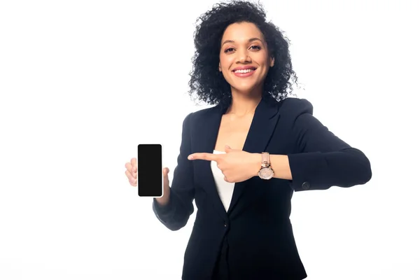 Vista frontal da mulher afro-americana apontando para o smartphone, sorrindo e olhando para a câmera isolada no branco — Fotografia de Stock