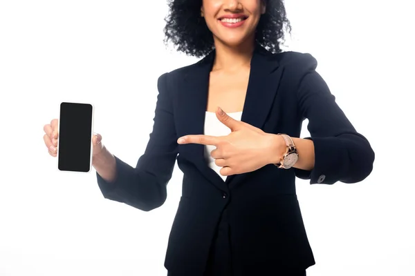 Cropped view of african american woman pointing at smartphone and smiling isolated on white — Stock Photo