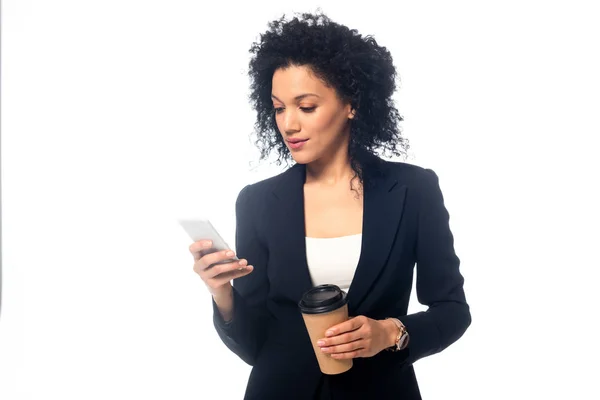 Фронтальный вид африканской бизнесвумен с одноразовой чашкой кофе, смотрящей на смартфон, изолированный на белом — стоковое фото