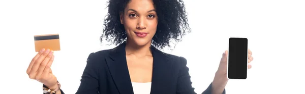 Donna d'affari afroamericana che presenta carta di credito e smartphone e sorride isolata sul bianco, scatto panoramico — Foto stock