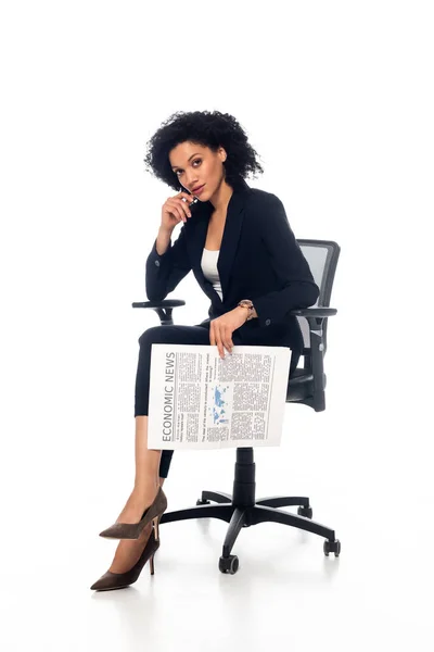 Afroamerikanische Geschäftsfrau im Bürostuhl hält Zeitung in der Hand und blickt in die Kamera auf weiß — Stockfoto