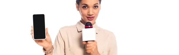 Африканский американский журналист, говорящий в микрофон и представляющий смартфон изолированный на белом, панорамном снимке — стоковое фото