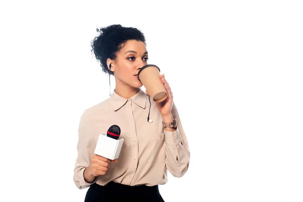 Vista frontal de periodista afroamericano con micrófono y auriculares bebiendo café aislado en blanco - foto de stock
