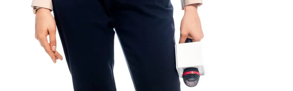 Vista recortada del periodista afroamericano en pantalones negros con micrófono aislado en blanco, plano panorámico - foto de stock