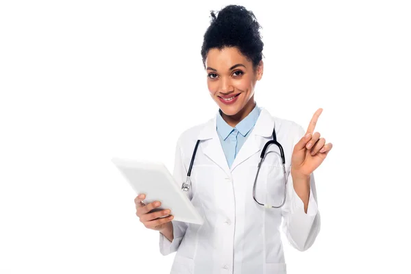 Vista frontale del medico afroamericano con stetoscopio e tablet digitale puntato con dito isolato su bianco — Foto stock