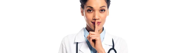Médecin afro-américain avec stéthoscope montrant calme et regardant la caméra isolée sur blanc, panoramique — Photo de stock