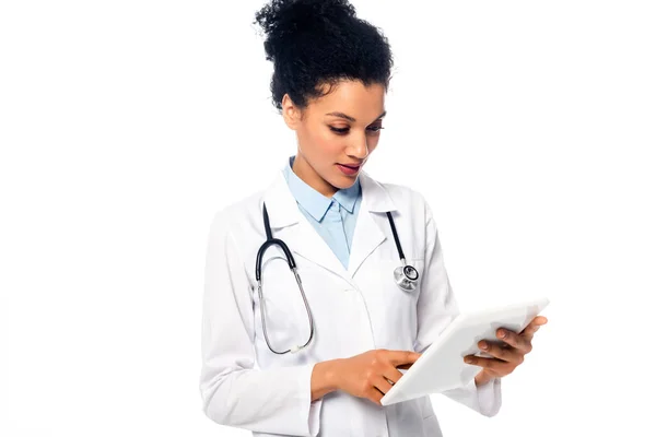 Front view of african american doctor with stethoscope focused on using digital tablet isolated on white — Stock Photo