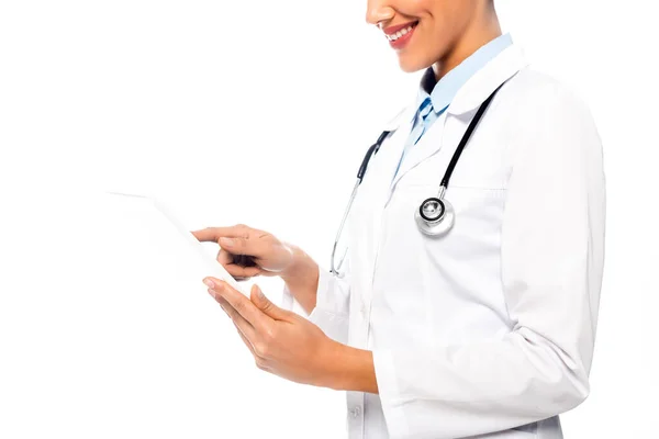 Vista recortada del médico afroamericano con estetoscopio usando tableta digital y sonriendo aislado en blanco - foto de stock