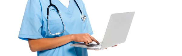 Cropped view of african american nurse with stethoscope focused on using laptop isolated on white, panoramic shot — Stock Photo