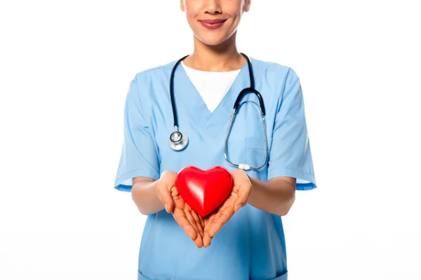 Vista recortada de enfermera afroamericana con estetoscopio mostrando el corazón decorativo y sonriendo aislado en blanco - foto de stock