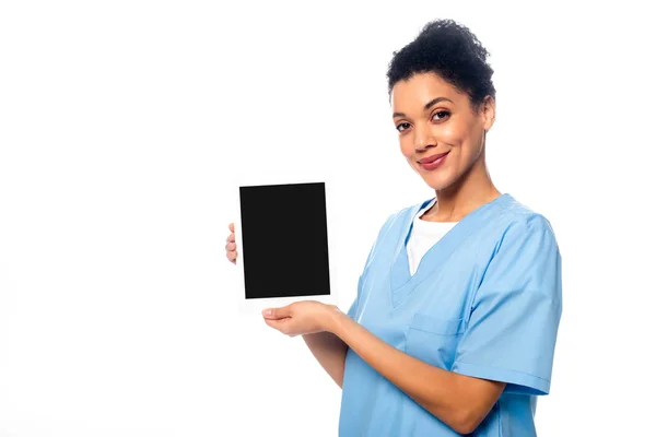 African american nurse looking at camera and showing digital tablet isolated on white — Stock Photo