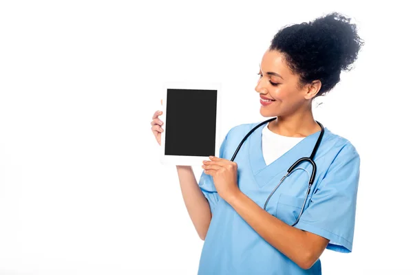 Enfermera afroamericana sonriendo y mostrando tableta digital aislada en blanco - foto de stock