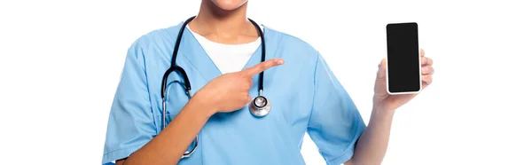 African american nurse with stethoscope presenting smartphone isolated on white, panoramic shot — Stock Photo