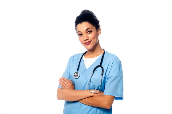 Vista frontal de enfermera afroamericana con brazos cruzados sonriendo aislada sobre blanco - foto de stock