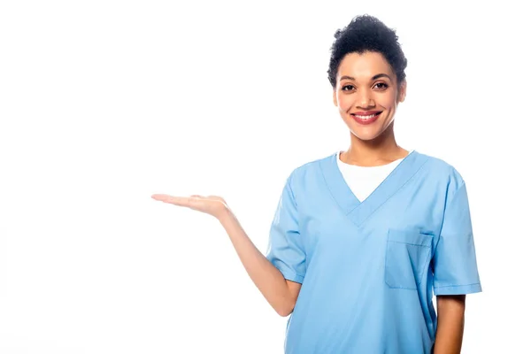 African american nurse smiling and pointing with hand isolated on white — Stock Photo