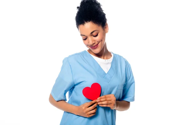 Positive african american nurse holding decorative heart isolated on white — Stock Photo