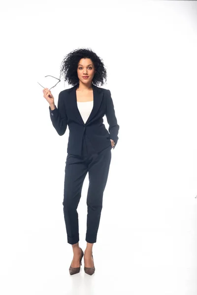 Full length view of confident african american businesswoman in suit with glasses on white — Stock Photo