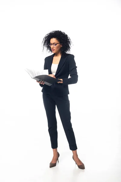 Vista completa de la mujer de negocios afroamericana mirando en carpeta sobre fondo blanco - foto de stock