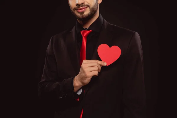 Vista cortada de homem elegante segurando papel em forma de coração vermelho isolado em preto — Fotografia de Stock