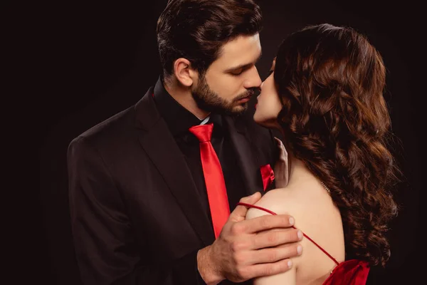 Елегантний чоловік цілує дівчину під час знімання сукні ізольовано на чорному — стокове фото