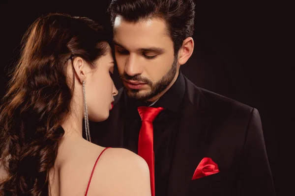 Beautiful woman standing near handsome man in formal wear isolated on black — Stock Photo