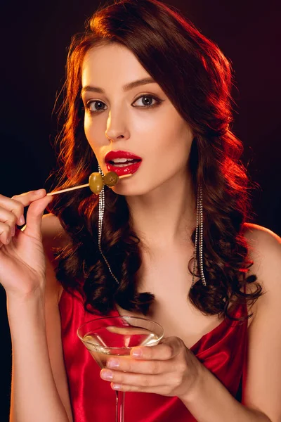 Attractive girl holding stick with olives and glass of vermouth isolated on black — Stock Photo