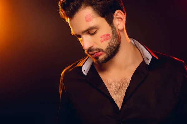 Schöner Mann mit rotem Lippenstift im Gesicht auf schwarzem Hintergrund mit Beleuchtung — Stockfoto