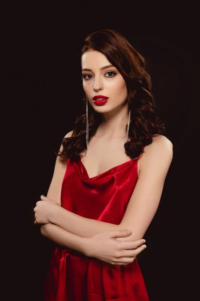 Elegante chica en vestido rojo mirando a la cámara aislada en negro - foto de stock